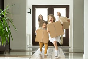 Excited kids running holding boxes, family moving in new house on san clemente mortgage broker's website