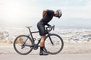 Man athlete and cycling with bike back pain and mountain road with sports injury exercise or adventure Male person cyclist and inflammation in training physical activity and fitness in nature Man bike back pain