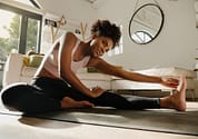 Woman exercising at home stretching legs and warming up stretching for chiropractic health