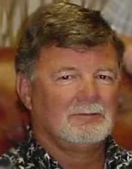 Portrait of a middle-aged man with short gray hair and a goatee wearing a patterned shirt.