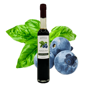 a bottle of balsamic vinegar in front of basil and blueberry