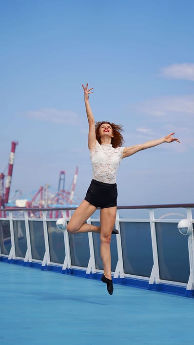 Sporty slim dancer fulfills jumping poses promenade deck of cru