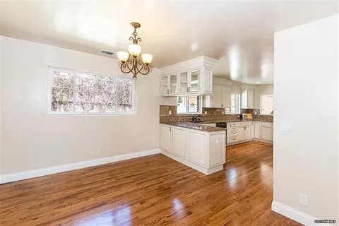 gallery4-a | Advance Installations Open-concept living and kitchen area with hardwood floors, white cabinets, and island in the center.