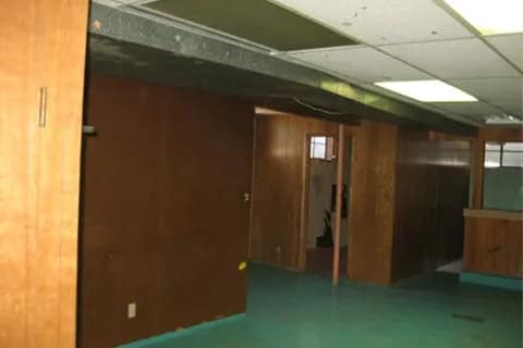 gallery6-b | Advance Installations Empty office hallway with brown wood paneling, green carpet, and a drop ceiling; open doors along the corridor.