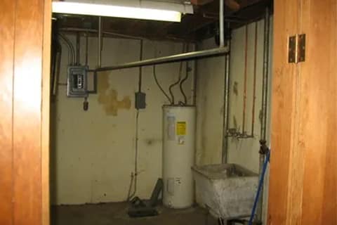 gallery7-b | Advance Installations Utility room in a basement with a white water heater, exposed pipes, and a sink.
