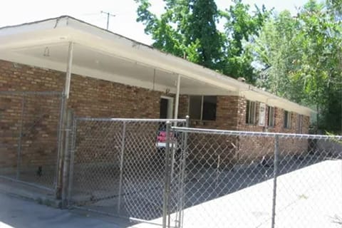 gallery9-b | Advance Installations Front view of a low, flat-roofed brick building with a chain-link fence and gate in the foreground.