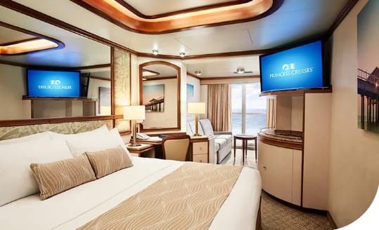 Mini Suite | Holiday Planit Elegant cruise cabin with a large bed, warm wood accents, and twin TVs displaying Princess Cruises in-room content.