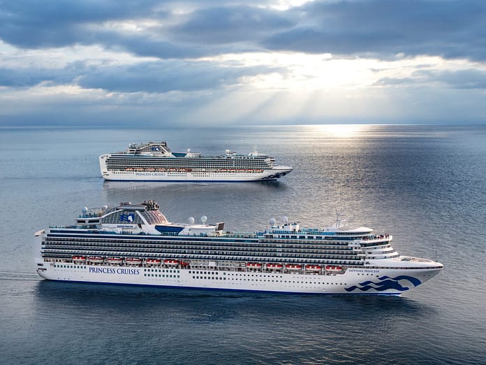 default | Holiday Planit Two large Princess Cruises ships sail on calm blue water under a cloudy sky, with the word PRINCESS CRUISES visible on the hull of the foreground vessel.