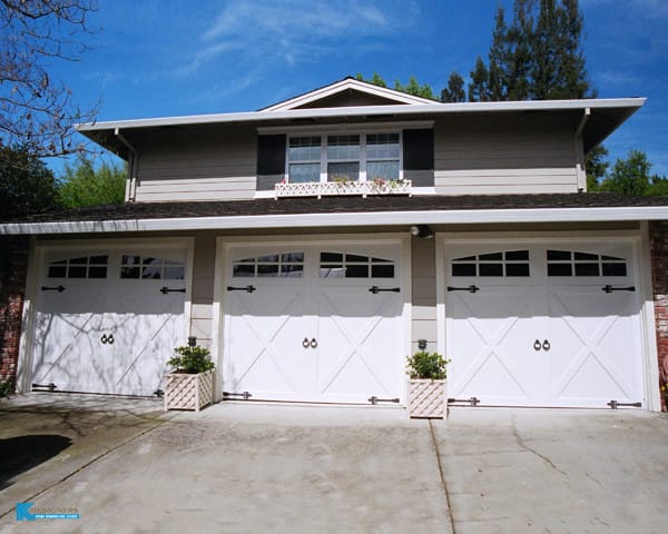 After photo of the exterior of a remodeled three-car garage with white window garage doors.