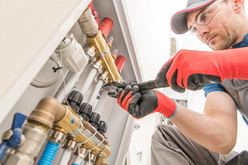 Residential House Floor Heating Valves Adjustment. Plumbing and Heating Technician at Work. Residential House Floor Heating Valves Adjustment. Plumbing and Heating Technician at Work.
